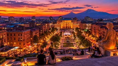 Evening view of Yerevan from Cascade at sunset with city lights and Mount Ararat