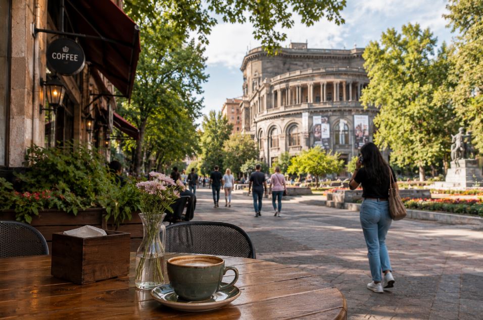 Cup of coffee at an outdoor café in Yerevan with people walking nearby